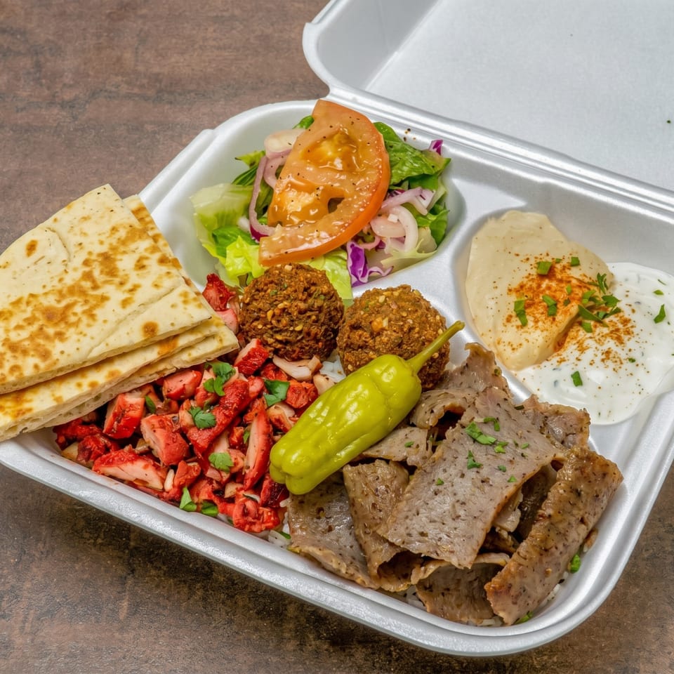 A takeout container filled with chicken tikka, gyro meat, falafel, salad, hummus, and pita bread.