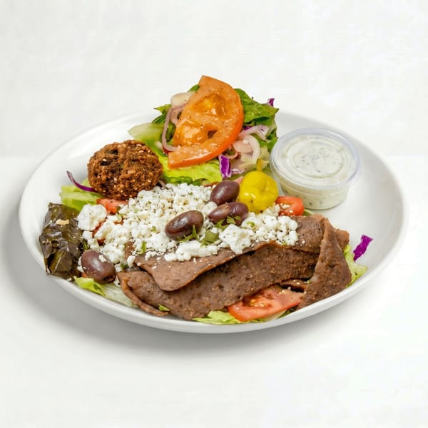Gyro meat salad with feta, olives, falafel, dolma, and a side of dressing.
