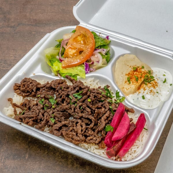 Takeout container with beef shawarma, rice, salad, hummus, yogurt sauce, and pickled turnips.